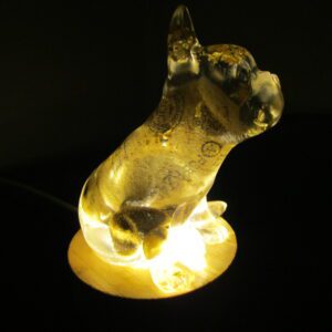 Bouledogue Tonneau Un Trésor Lumineux et Artisanal Laissez-vous charmer par "Bouledogue Tonneau", une sculpture lumineuse unique qui allie l'élégance à l'originalité. Cette pièce d'exception est façonnée à la main en résine, incrustée de feuilles d'or, de pierres naturelles et d'un bouchon de vin recyclé. Elle illumine votre intérieur d'une lumière douce et d'une touche de magie. Un Design Unique et Précieux, Fruit d'une Création Artisanale Chaque "Bouledogue Tonneau" est une œuvre d'art unique, sculptée avec passion et créativité. La résine transparente révèle les inclusions précieuses : des feuilles d'or scintillantes, des pierres naturelles aux couleurs douces et un bouchon de vin recyclé, symbole d'une démarche éco-responsable. Le design original de cette sculpture apporte une touche d'humour et de raffinement à votre décoration. Une Lumière Douce et Enchanteuse, Créant une Ambiance Magique La lumière émanant du socle illumine la résine et fait scintiller les inclusions, créant un spectacle visuel captivant. Ce bouledogue lumineux est idéal pour créer une ambiance chaleureuse et accueillante. Il apporte une touche de magie et d'originalité à votre intérieur, transformant votre espace en un lieu enchanteur. Un Objet Décoratif Unique et Précieux, Témoin d'un Engagement "Bouledogue Tonneau" est bien plus qu'une simple sculpture. C'est une pièce de collection qui témoigne d'un savoir-faire artisanal et d'un engagement pour l'environnement. Son design unique et ses matériaux précieux en font un objet décoratif exceptionnel. Caractéristiques Matériaux : Résine, feuilles d'or, pierres naturelles, bouchon de vin recyclé, socle lumineux Fabrication : Artisanale, chaque pièce est unique Design : Original et précieux, s'adapte à tous les styles d'intérieur Lumière : Douce et chaleureuse, crée une ambiance enchanteresse Conseils d'Entretien Pour préserver la beauté de votre "Bouledogue Tonneau", nous vous recommandons de le nettoyer délicatement avec un chiffon doux. Évitez l'exposition prolongée au soleil et aux sources de chaleur intense. Laissez-vous séduire par le charme et l'éclat de "Bouledogue Tonneau". Il est une création unique qui apportera une touche de magie et de lumière à votre intérieur.