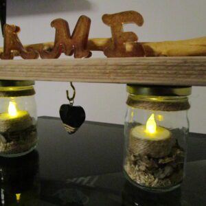 Le Murmure de l'Âme "Apportez une touche d'originalité à votre décoration avec ce luminaire DIY. Deux bocaux en verre, transformés en bougeoirs, sont reliés par une structure en bois brut. Des lettres en bois, formant le mot "AME", apportent une touche décorative et personnalisée. Un cœur en bois suspendu complète cette création unique."