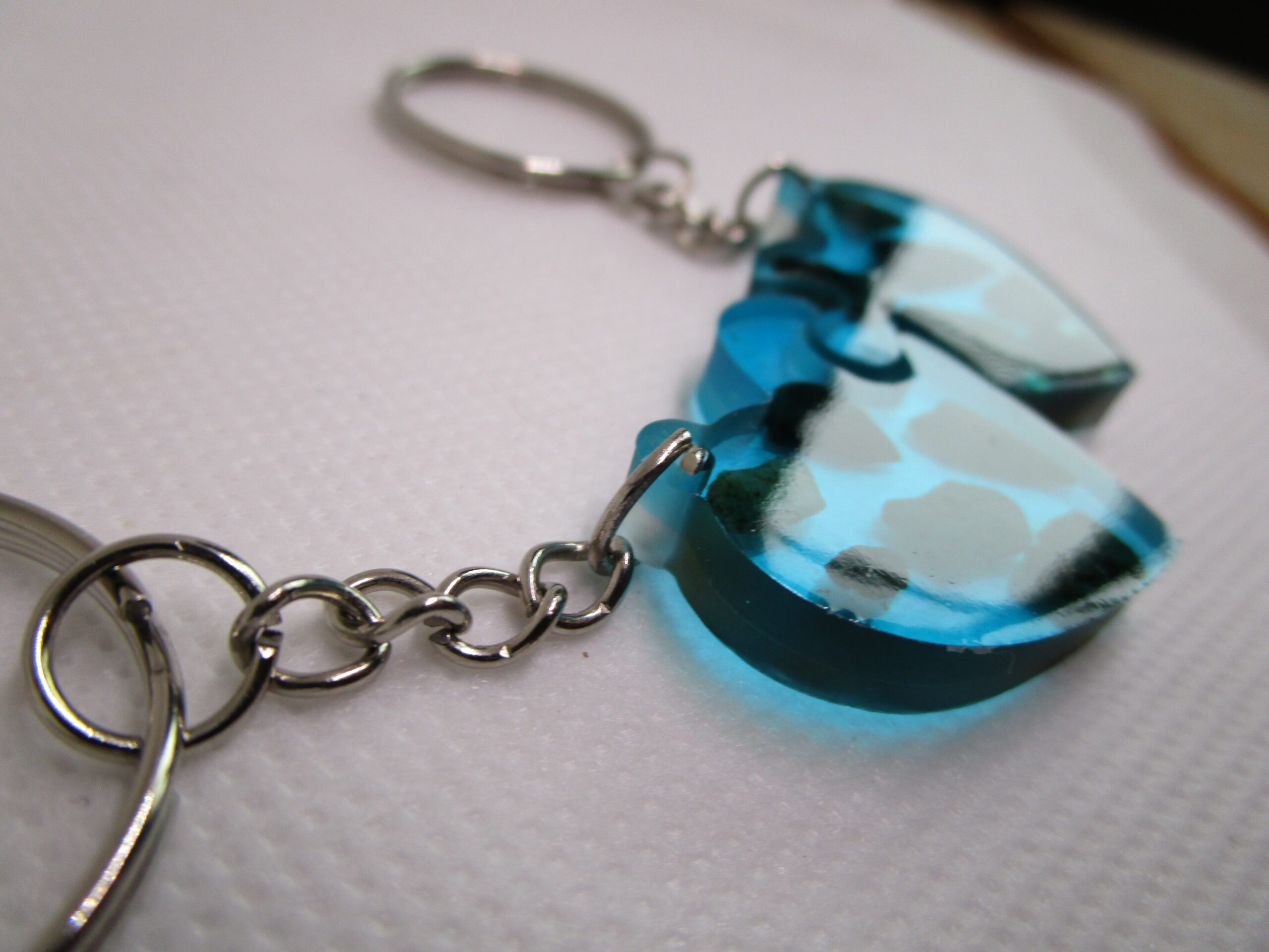 "Cœur Maldives" en résine bleu lagon avec des pierres naturelles incrustées. Description : Porte-clés "Cœur Maldives" : Un bijou unique pour les amoureux de l'océan. Ce porte-clés artisanal est une véritable invitation au voyage. Sa résine bleu lagon évoque les eaux cristallines des Maldives, tandis que les petites pierres naturelles incrustées ajoutent une touche d'originalité et de raffinement. La forme de cœur symbolise l'amour et la passion, faisant de ce porte-clés un cadeau idéal pour un couple ou un ami spécial. Chaque pièce est unique, fabriquée à la main avec soin et passion. Les détails sont minutieux et la qualité est irréprochable. Ce porte-clés est non seulement un bel objet, mais aussi un accessoire pratique pour garder vos clés à portée de main. Offrez-vous ou offrez un morceau de rêve avec le porte-clés "Cœur Maldives".
