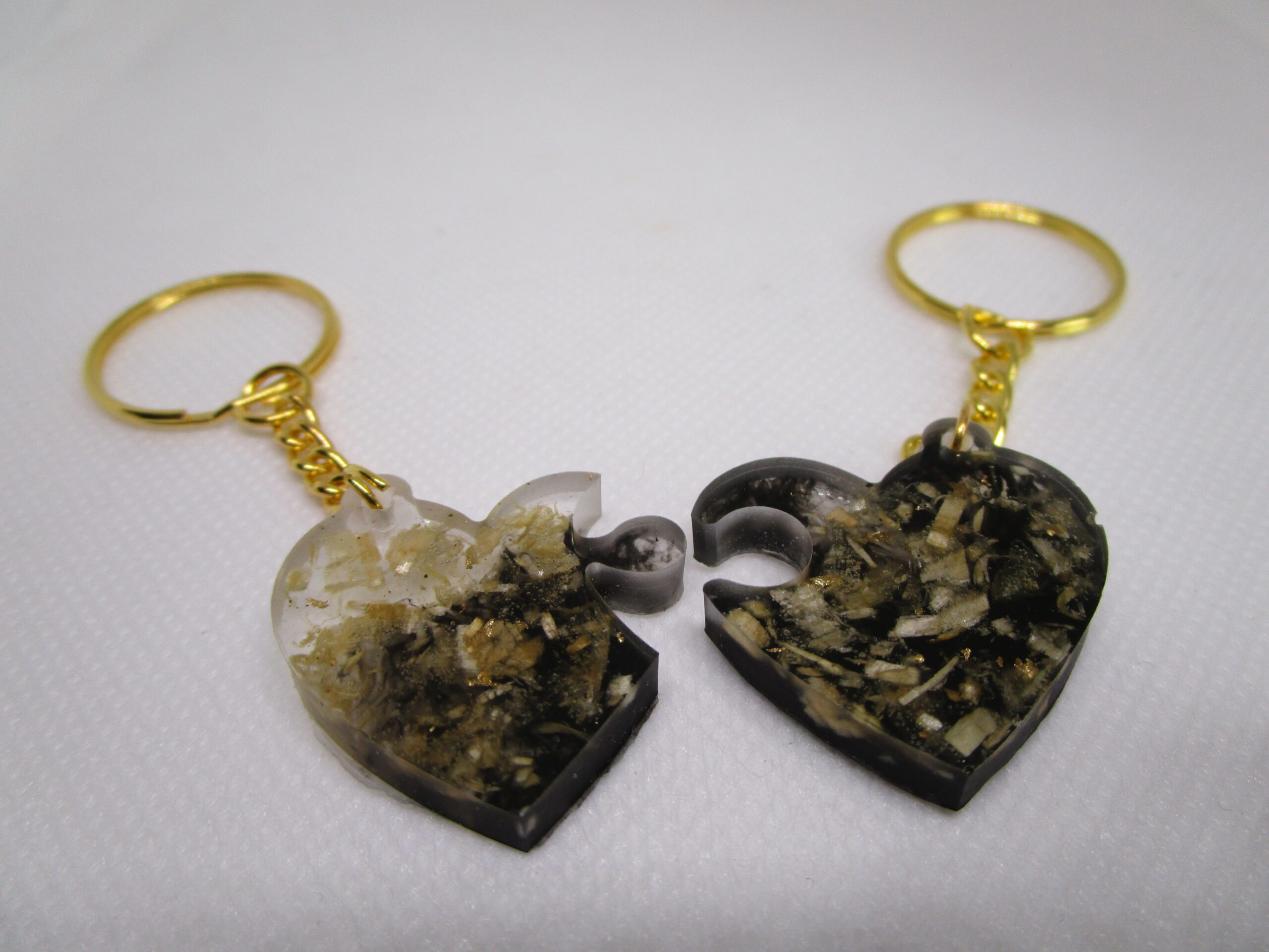 Cœurs de copeaux duo de porte clé artisanaux. Chaque porte-clé est un demi-cœur en résine noire et transparente, incrusté de copeaux de bois. Les deux moitiés s'assemblent pour former un cœur complet. artisanaux. Chaque porte-clé est un demi-cœur en résine noire et transparente, incrusté de copeaux de bois. Les deux moitiés s'assemblent pour former un cœur complet.