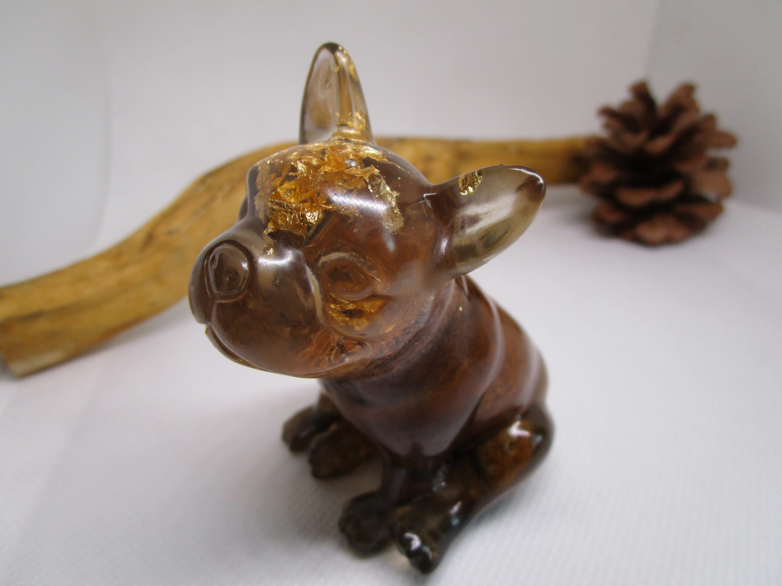Figurine artisanale "Bouledogue Deluxe" un bouledogue français en résine transparente avec des feuilles d'or et des pierres. Un bouchon de champagne est intégré à la figurine. La figurine est une pièce unique, faite à la main. Elle combine différents matériaux : résine, feuilles d'or, pierres et un bouchon de champagne. Elle est idéale pour décorer votre intérieur ou offrir en cadeau.
