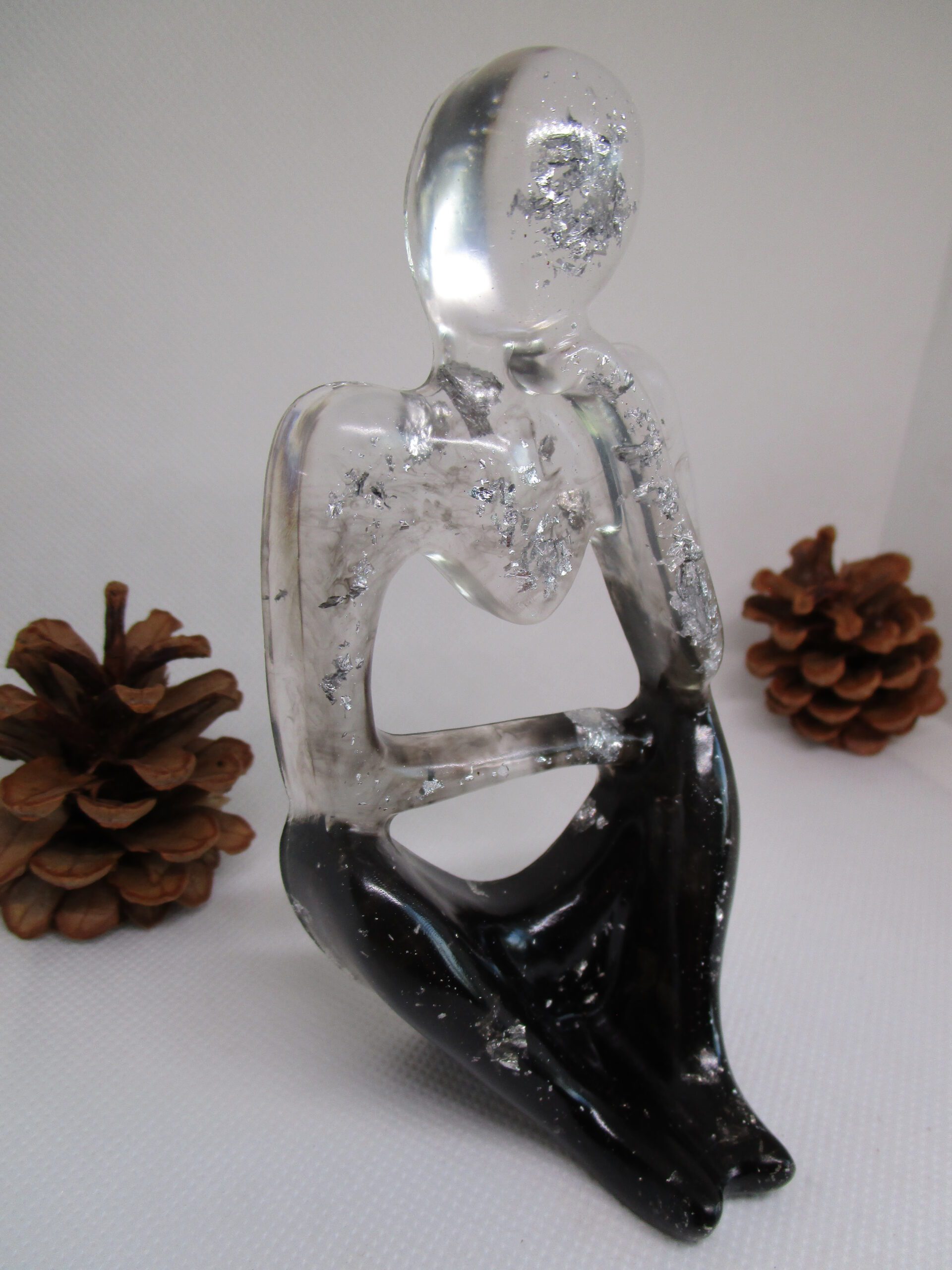 Le Penseur Élégant Une Ode à la Réflexion, Capturée en Résine et Argent Introduction : L'Éveil de la Pensée D'abord, laissez-vous séduire par cette sculpture unique. Elle fige l'instant de la réflexion. Ensuite, l'artiste donne vie au "Penseur Élégant". Cette œuvre d'art incarne la beauté de l'esprit. De plus, chaque détail est façonné avec soin. Ainsi, cette création est le fruit d'un savoir-faire artisanal. La Résine : Un Jeu de Transparence et de Profondeur L'artiste privilégie la résine pour sa clarté. En effet, ce matériau danse avec la lumière. Par ailleurs, il crée un contraste saisissant. La résine noire évoque le mystère. En revanche, la résine transparente symbolise la lucidité. L'Argent : Un Éclat Précieux et Lumineux Des éclats d'argent illuminent la sculpture. Ils apportent une touche de raffinement. L'argent symbolise la pureté et la sagesse. De surcroît, il représente la valeur de la pensée. Ces inclusions argentées rendent chaque pièce exclusive. Elles captent la lumière et scintillent délicatement. Un Design Épuré : L'Harmonie des Formes et des Lignes Le design de la sculpture est minimaliste. Il met en lumière la silhouette du penseur. Les lignes sont fluides et gracieuses. Elles invitent à la méditation. La forme épurée favorise la concentration. Elle permet de se recentrer sur l'essentiel. Une Création Artisanale : L'Expression d'une Passion L'artiste façonne chaque sculpture à la main. Il y insuffle une part de son âme. Ce travail artisanal garantit l'authenticité. Vous acquérez une œuvre d'art véritable. Cette sculpture reflète une passion sincère. Un Objet de Décoration : Une Source d'Inspiration Cette sculpture trouve sa place dans votre intérieur. Elle apporte une atmosphère sereine et élégante. Disposez-la sur un bureau ou une étagère. Elle devient un élément central de votre décoration. Elle suscite la curiosité et l'émerveillement. Elle encourage à la réflexion et à la contemplation. Conclusion : Un Investissement Artistique et Émotionnel "Le Penseur Élégant" est bien plus qu'une simple sculpture. C'est une pièce de collection et un investissement durable. Elle traverse le temps et les tendances. Elle conserve sa valeur et sa beauté. Offrez-vous cette œuvre d'art unique. Elle témoigne de votre goût pour l'art et l'originalité. Vous possédez un fragment de l'âme de l'artiste.