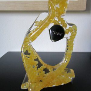 Sculpture "Penseur Gastronomique" en résine transparente, silhouette humaine assise en position de réflexion. Des pâtes jaunes sont incrustées dans la résine. Un galet noir avec l'inscription "CHEF" en lettres argentées est visible au niveau de la poitrine.