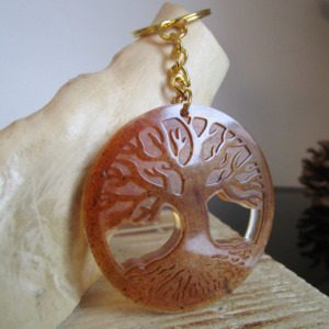 La forêt sacrée "Ce porte-clés ovale est un hommage à la nature. La sciure de bois, matière naturelle et chaleureuse, lui confère un aspect authentique. Le motif d'arbre de vie, symbole de force et de longévité, renforce cette connexion avec la nature."