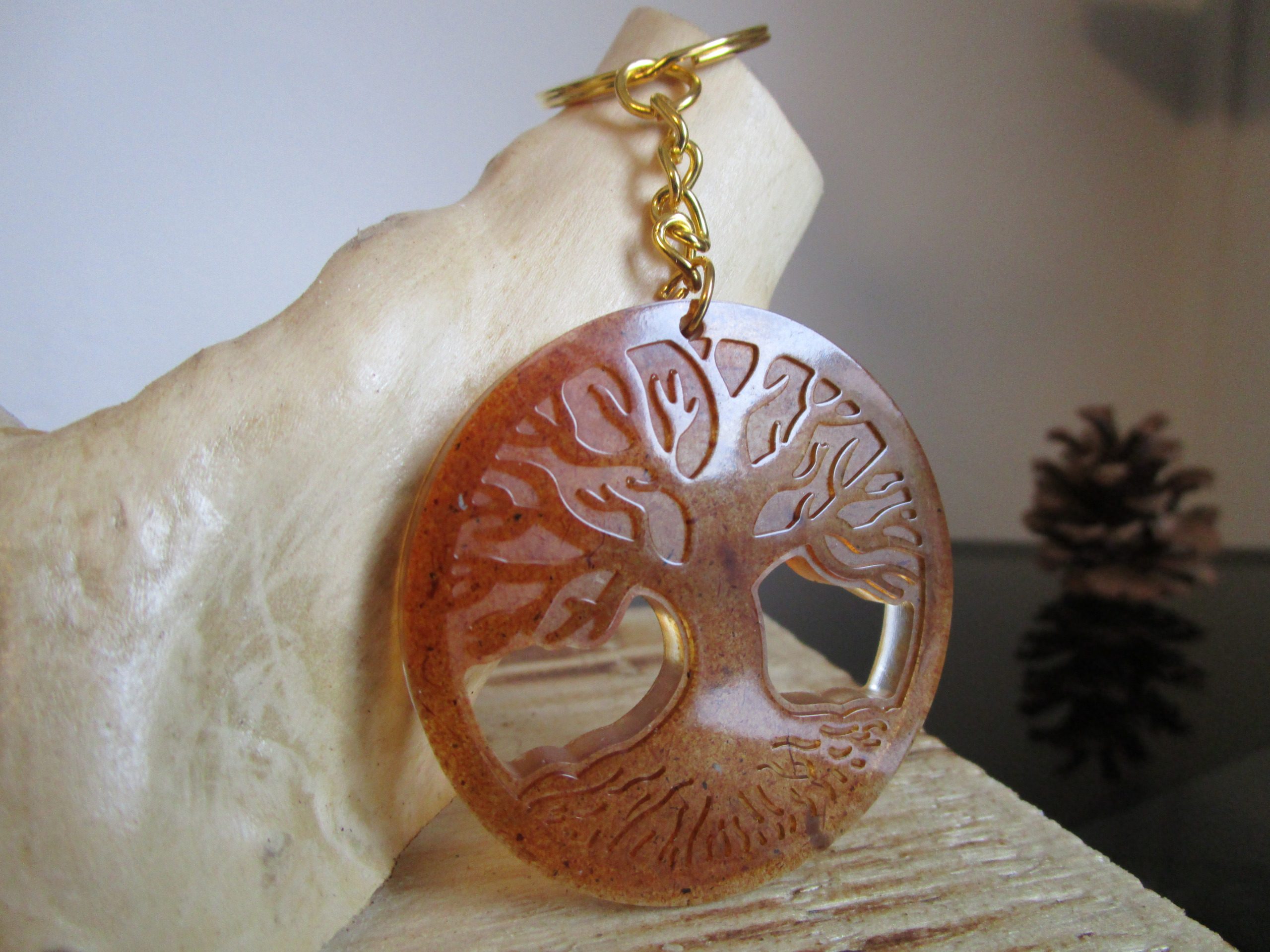 La forêt sacrée "Ce porte-clés ovale est un hommage à la nature. La sciure de bois, matière naturelle et chaleureuse, lui confère un aspect authentique. Le motif d'arbre de vie, symbole de force et de longévité, renforce cette connexion avec la nature."