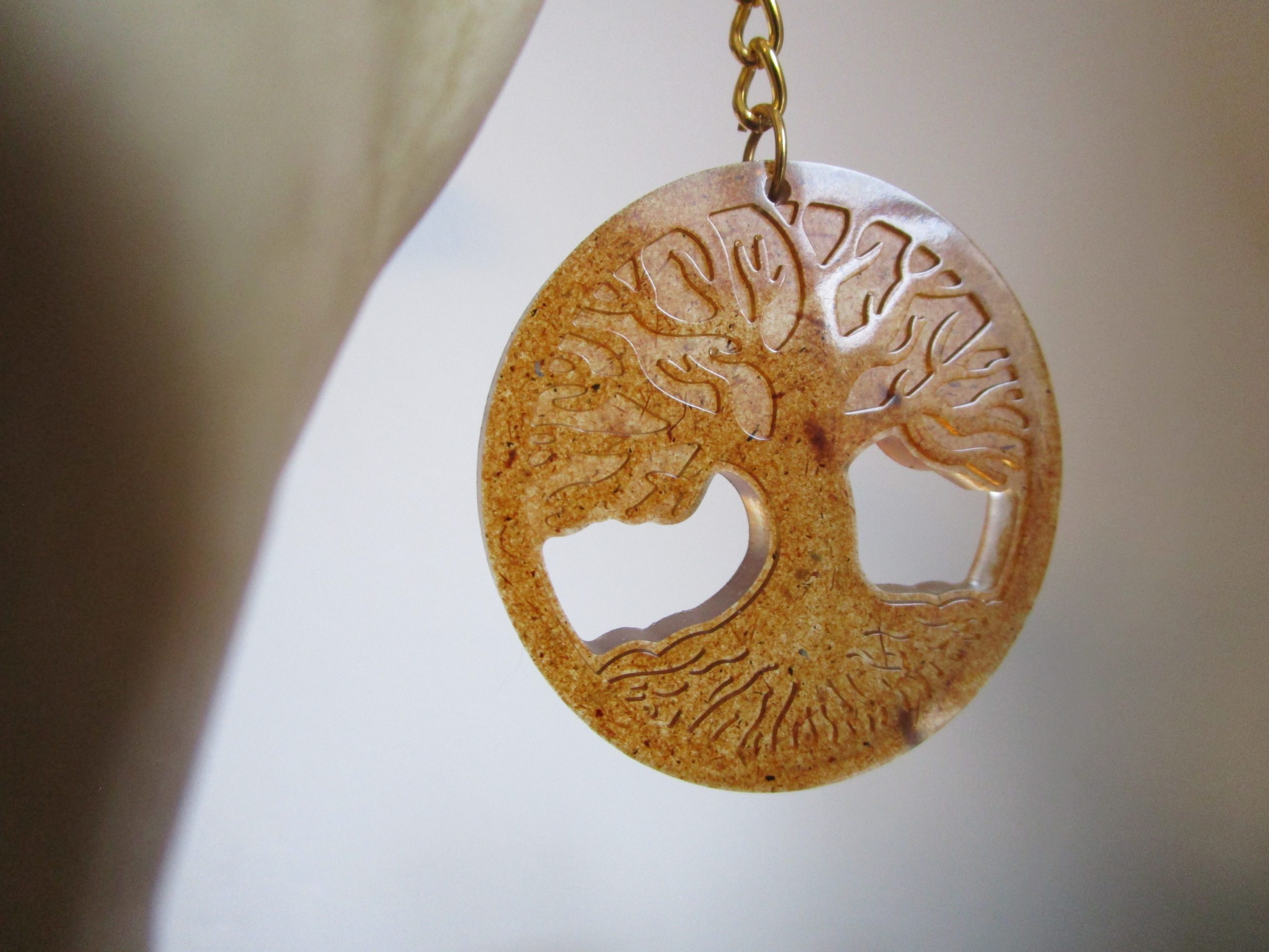 "Ce porte-clés ovale est un hommage à la nature. La sciure de bois, matière naturelle et chaleureuse, lui confère un aspect authentique. Le motif d'arbre de vie, symbole de force et de longévité, renforce cette connexion avec la nature."