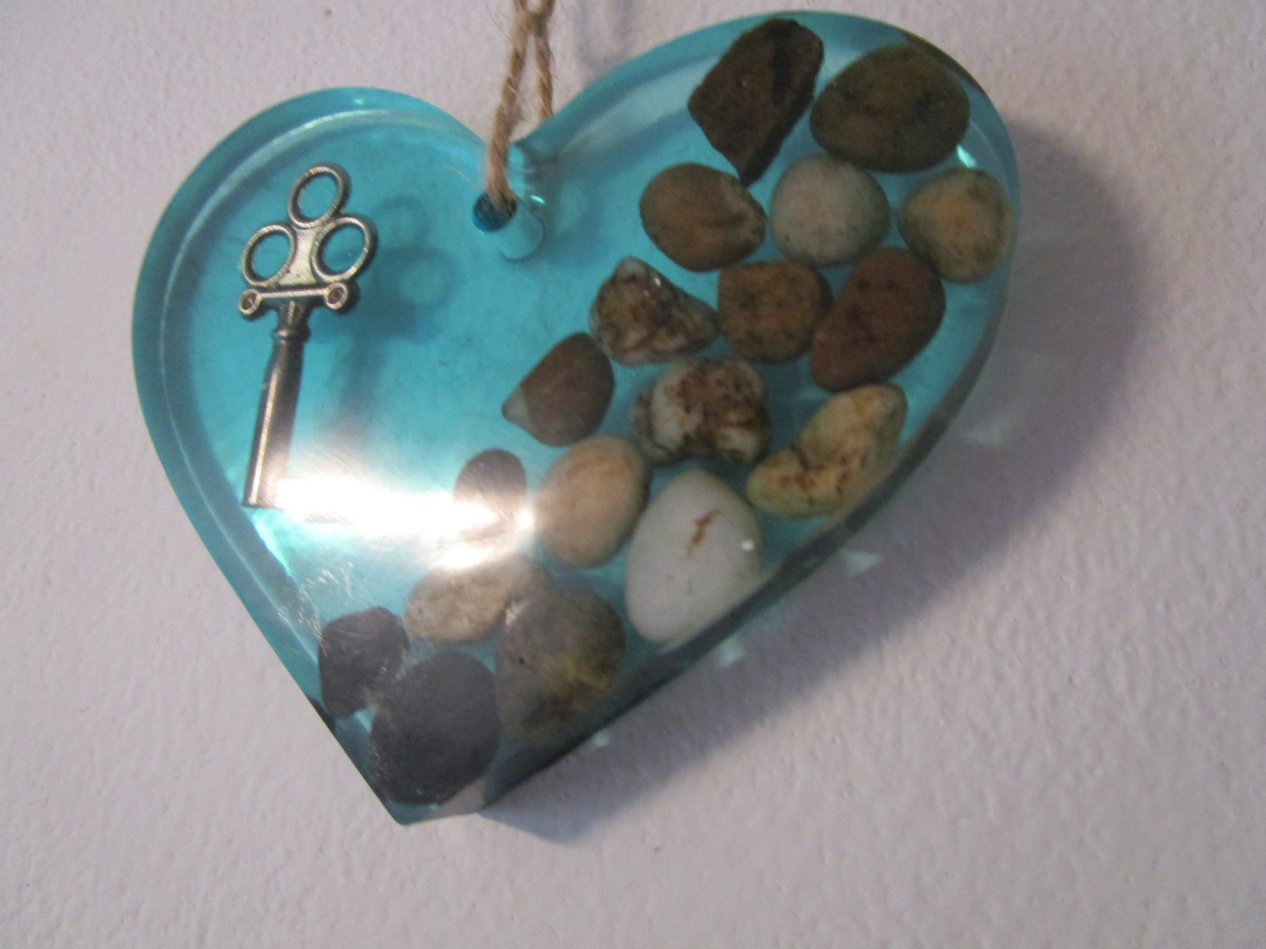 "Laissez l'énergie des pierres naturelles vous envelopper avec ce cœur en résine. Chaque pierre, choisie pour ses vibrations uniques, est mise en valeur par la transparence de la résine. Une clé, symbole de sagesse, ajoute une touche de magie à cette création. Accrochez ce cœur et laissez son énergie positive rayonner."