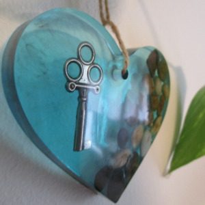 La Clé du Cœur "Laissez l'énergie des pierres naturelles vous envelopper avec ce cœur en résine. Chaque pierre, choisie pour ses vibrations uniques, est mise en valeur par la transparence de la résine. Une clé, symbole de sagesse, ajoute une touche de magie à cette création. Accrochez ce cœur et laissez son énergie positive rayonner."