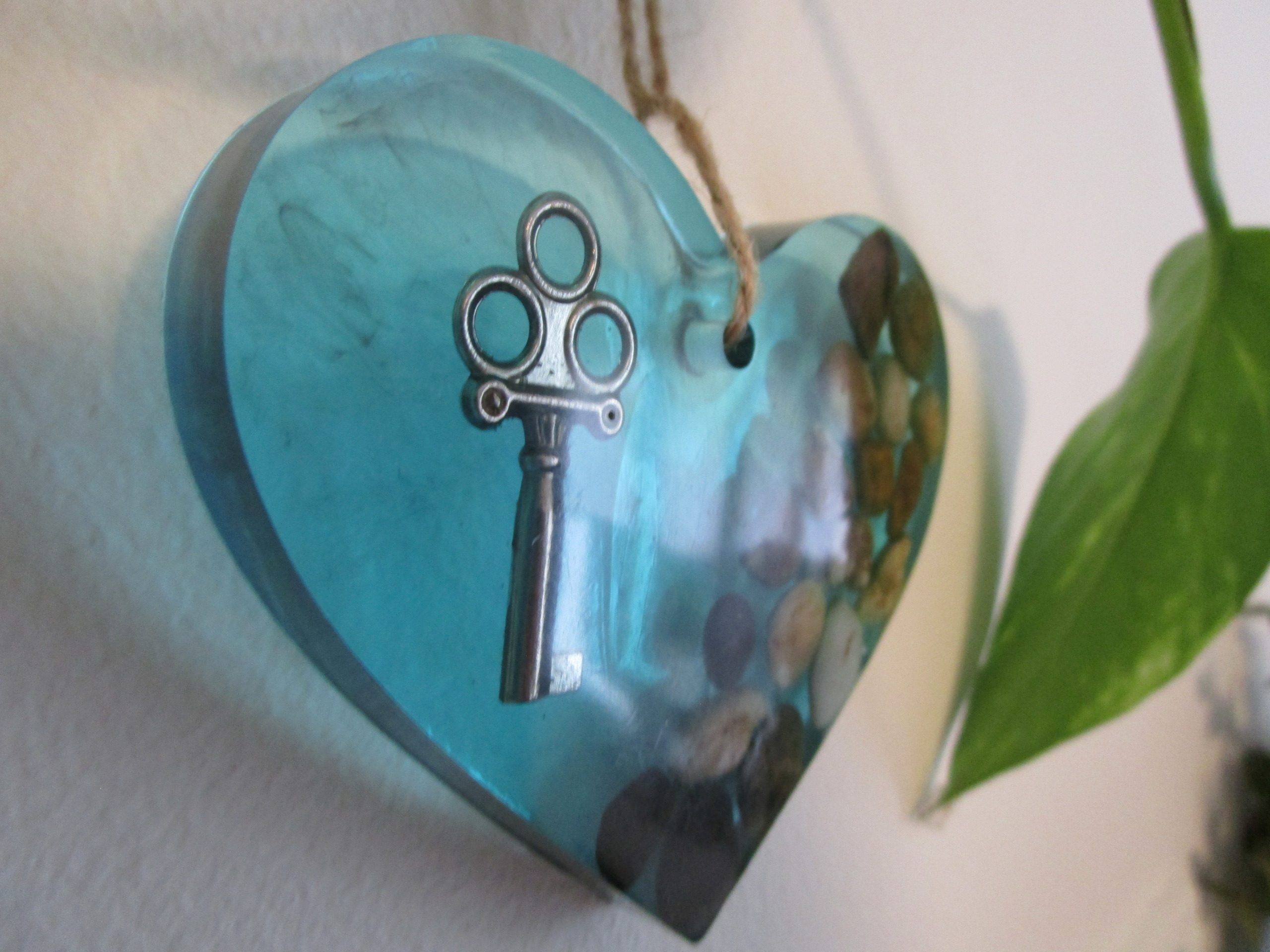 La Clé du Cœur "Laissez l'énergie des pierres naturelles vous envelopper avec ce cœur en résine. Chaque pierre, choisie pour ses vibrations uniques, est mise en valeur par la transparence de la résine. Une clé, symbole de sagesse, ajoute une touche de magie à cette création. Accrochez ce cœur et laissez son énergie positive rayonner."
