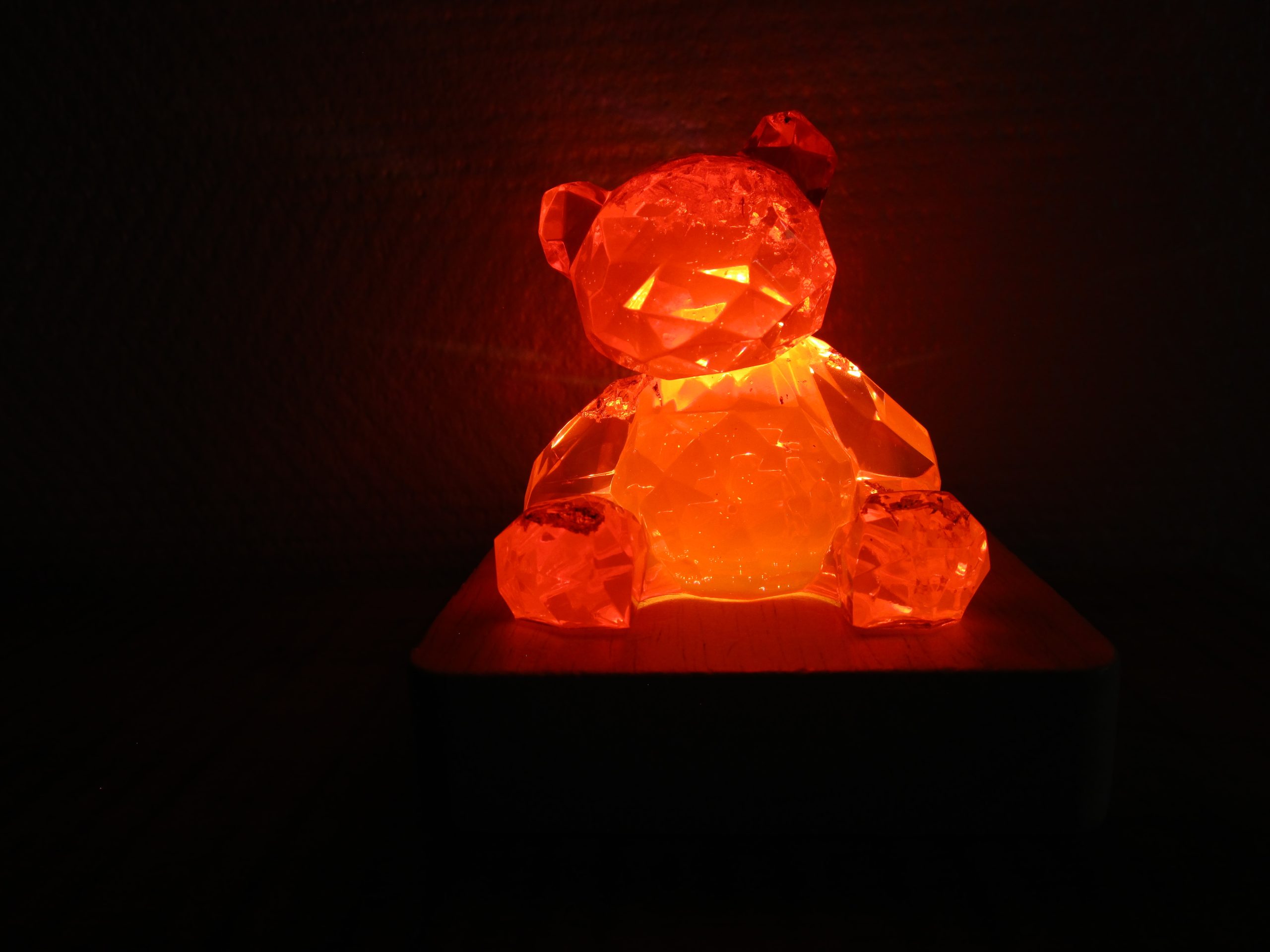 Posé sur son socle en bois forme carré, tel un joyau sur un coussin, l’ourson Ruby Light fait en résine rouge transparente règne sur son petit monde de lumière. Il est l’incarnation de la beauté, de la magie et de l’éclat éternel.