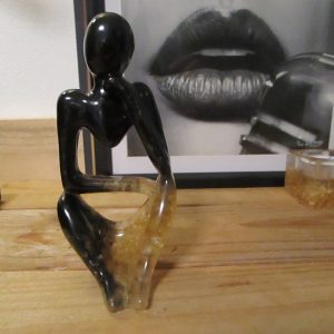 "Écho de Bois" est une sculpture unique, façonnée à la main. Sa silhouette féminine abstraite, en résine noire profonde, est illuminée par des fragments de bois incrustés, créant un contraste saisissant.