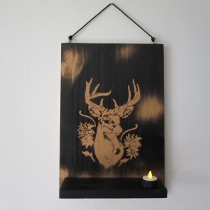 Apportez une touche urbaine et chaleureuse à votre intérieur avec cette veilleuse murale unique, entièrement réalisée à la main. Le fond, peint à la bombe avec un effet texturé, crée une toile de fond moderne et originale. Un cerf doré majestueux se détache sur ce fond sombre, créant un contraste saisissant. Une douce lueur émane de la bougie LED, ajoutant une dimension féerique à cette création.