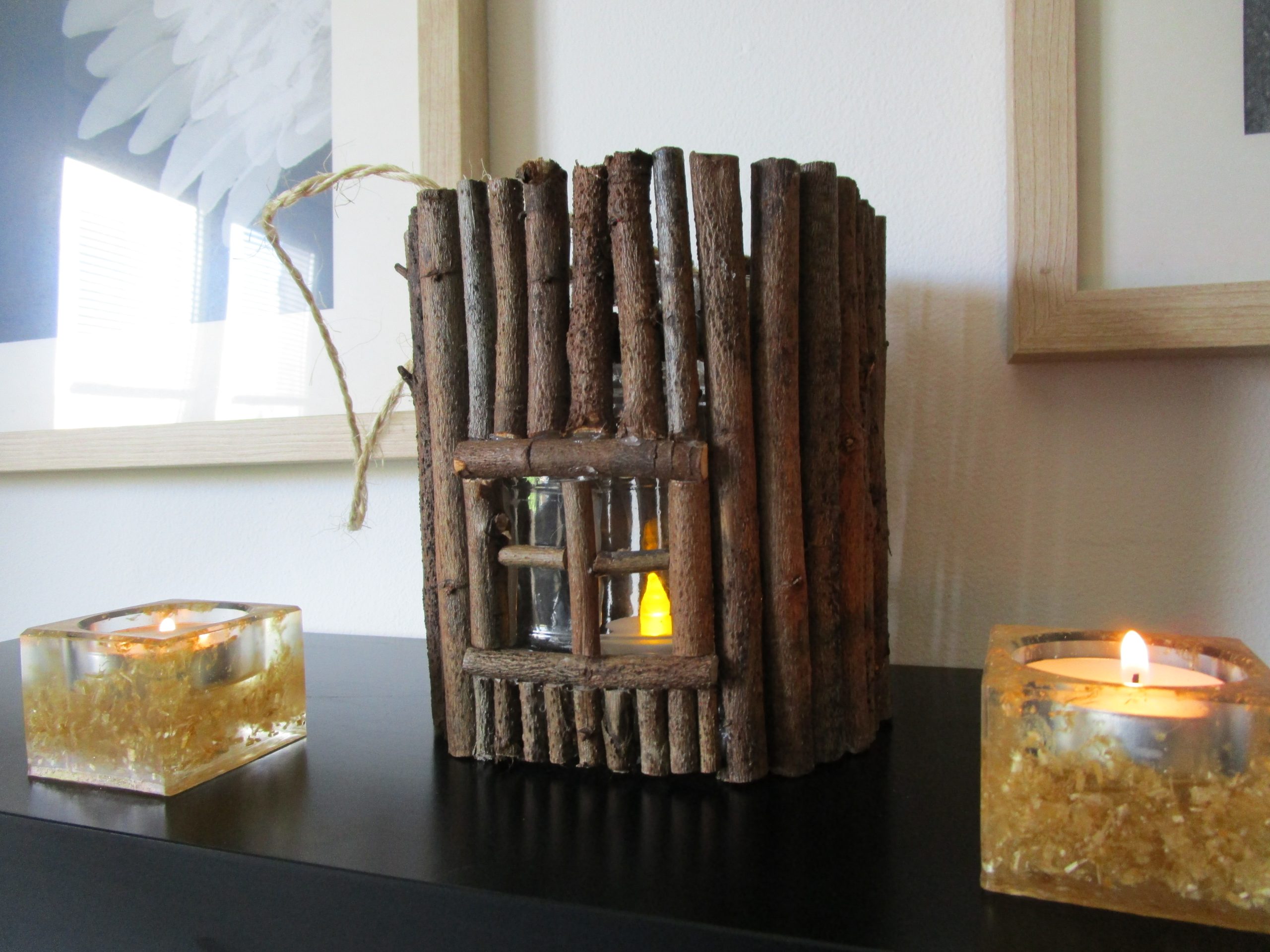 "Imaginez une petite maison, , conçue comme une lanterne. La base est un cylindre de verre lisse et frais, comme un pot de confiture. Tout autour, des dizaines de petits bâtonnets de bois, rugueux et irréguliers, sont collés côte à côte. Ils forment une surface texturée, comme l'écorce d'un arbre. À l'avant, une ouverture rectangulaire laisse entrevoir une lumière douce et chaude. Une petite flamme artificielle qui diffuse une lumière constante.