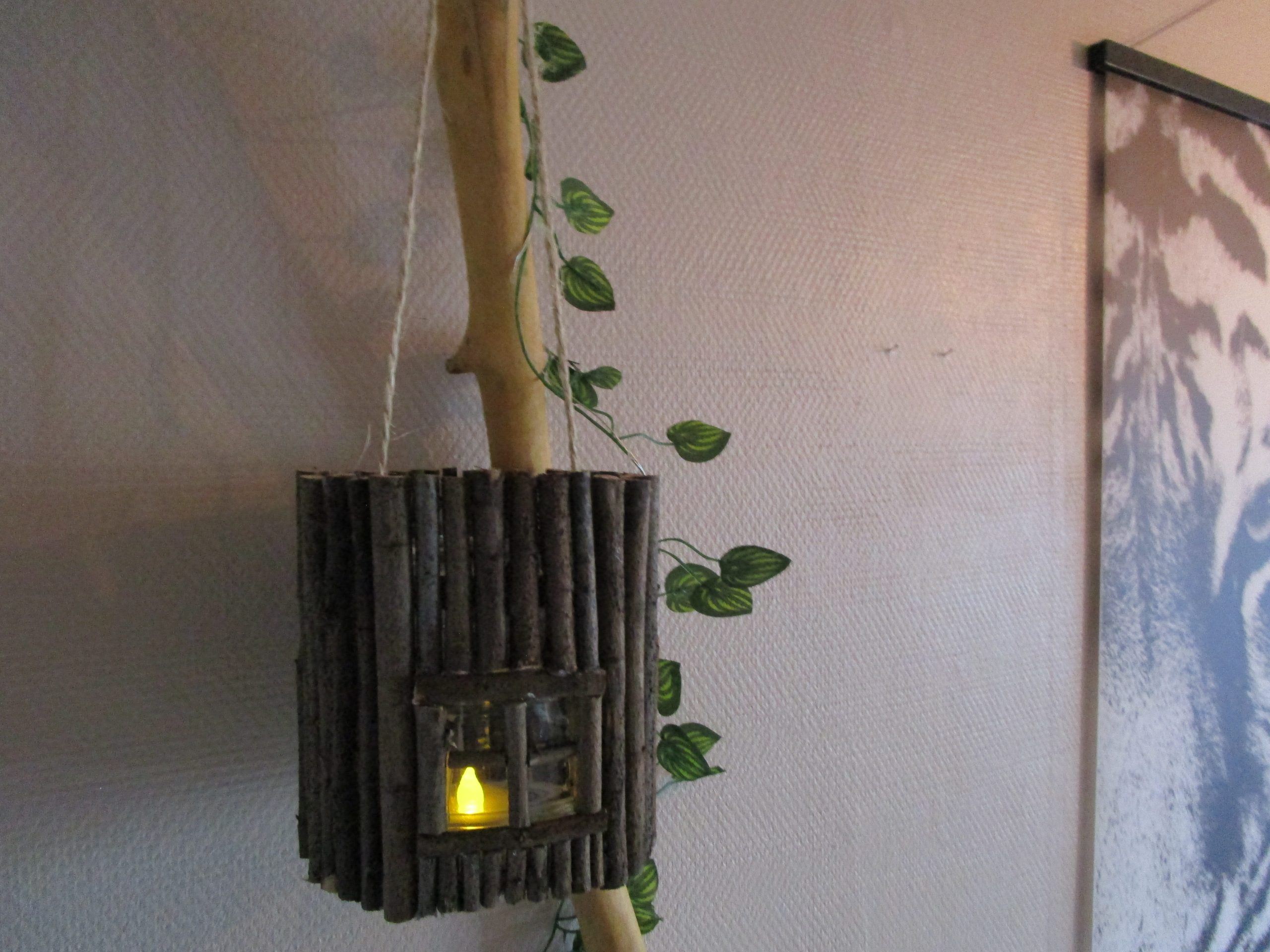 Le refuge du lutin laissez la magie de la forêt s'inviter chez vous avec cette lanterne unique. "Imaginez une petite maison, , conçue comme une lanterne. La base est un cylindre de verre lisse et frais, comme un pot de confiture. Tout autour, des dizaines de petits bâtonnets de bois, rugueux et irréguliers, sont collés côte à côte. Ils forment une surface texturée, comme l'écorce d'un arbre. À l'avant, une ouverture rectangulaire laisse entrevoir une lumière douce et chaude. Une petite flamme artificielle qui diffuse une lumière constante.