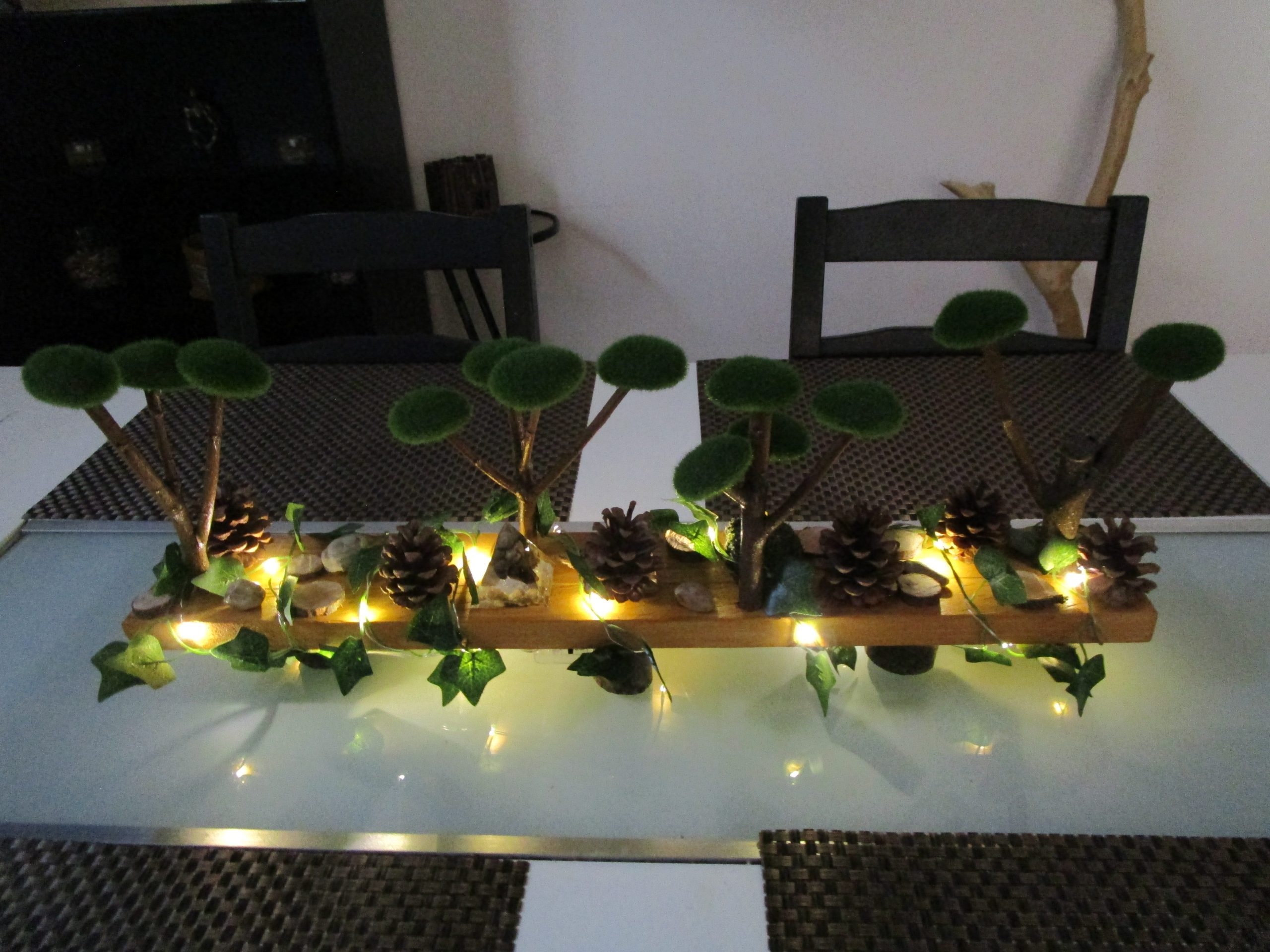 Dans un écrin de bois brut, un monde miniature s'éveille, un paysage enchanté où la nature et la lumière dansent en harmonie. Des arbres miniatures, couronnés de mousse douce, s'élèvent vers un ciel imaginaire, leurs branches délicates portant les promesses d'une forêt secrète .Cette création artisanale est un poème visuel, une invitation à la rêverie et à l'émerveillement. Elle nous transporte dans un monde où la nature et la lumière se rencontrent, où la beauté se révèle dans les détails les plus simples. Une bougie led est mise dans se décor, elle est recouverte de mousse naturelle.