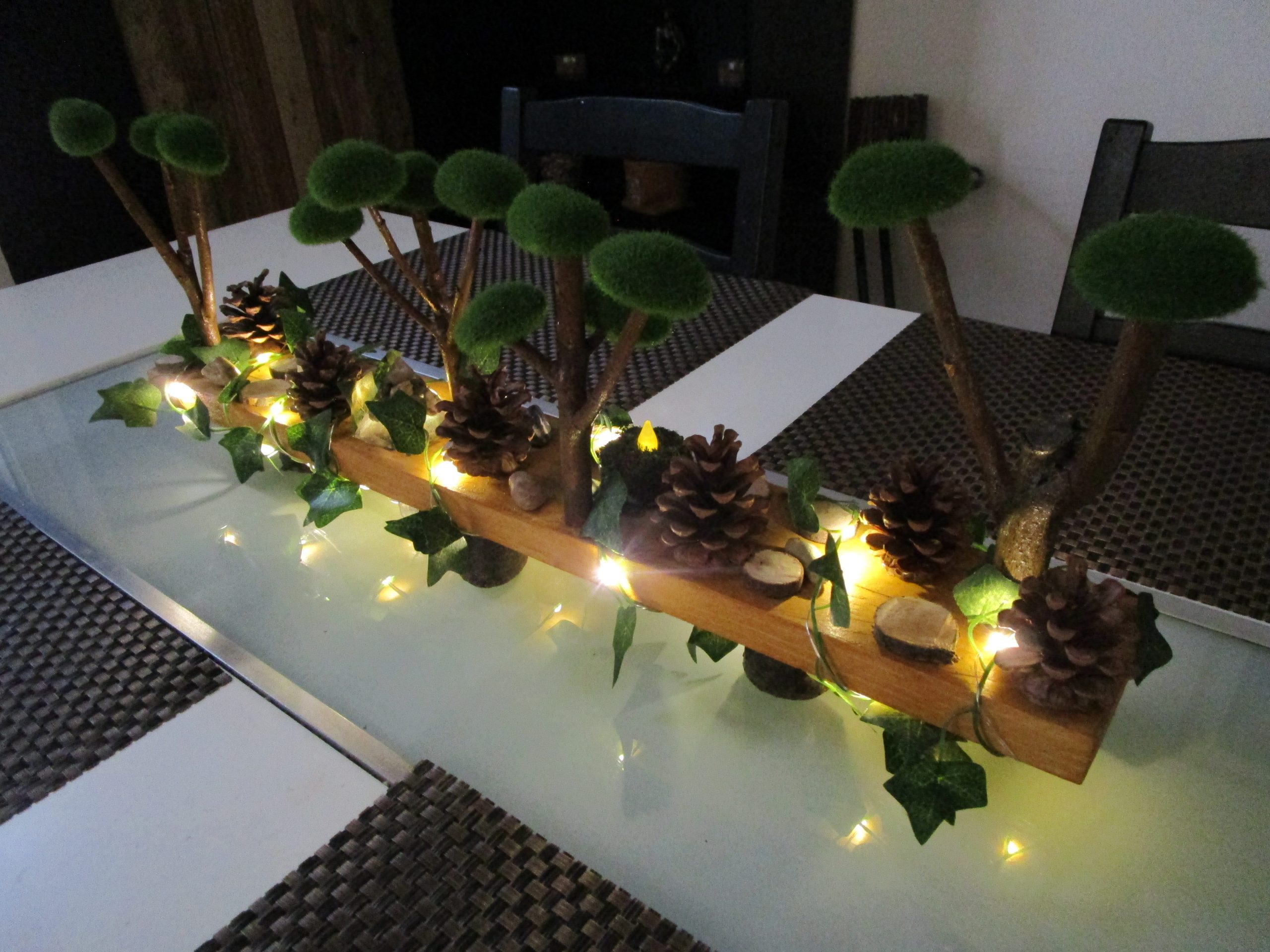 Dans un écrin de bois brut, un monde miniature s'éveille, un paysage enchanté où la nature et la lumière dansent en harmonie. Des arbres miniatures, couronnés de mousse douce, s'élèvent vers un ciel imaginaire, leurs branches délicates portant les promesses d'une forêt secrète .Cette création artisanale est un poème visuel, une invitation à la rêverie et à l'émerveillement. Elle nous transporte dans un monde où la nature et la lumière se rencontrent, où la beauté se révèle dans les détails les plus simples. Une bougie led est mise dans se décor, elle est recouverte de mousse naturelle.