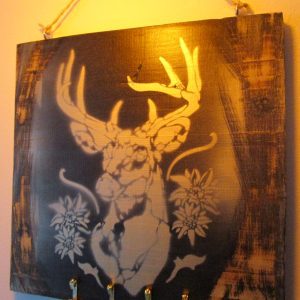 L'Esprit des Alpes "Tableau en bois recyclé, cerf peint à la bombe, touches alpines, crochets pour clés. L'empreinte de l'artiste signe cette pièce unique, où nature et fonctionnalité s'enlacent."