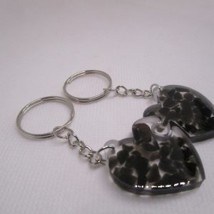 Deux porte-clés en forme de cœur, faits main en résine transparente avec des inclusions de pierres noires d'obsidienne.