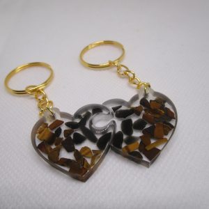 Amour Protégé. Porte-clés artisanaux en résine transparente avec des éclats d'obsidienne noire et d'œil de tigre dorée, formant un cœur.