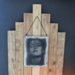 L'Écho du Silence D'une planche de bois recyclé renaît un visage féminin, esquissé par une myriade de points délicats. La main de l'artiste danse, déposant avec précision chaque touche de peinture, tandis que la bombe aérosol murmure des ombres douces et des lumières subtiles autour de cette apparition. Le pointillisme, tel un souffle retenu, construit les traits, les émotions, le mystère qui émane de cette figure silencieuse. Les imperfections du bois, loin d'être des défauts, racontent le passé du matériau, offrant une patine unique à ce portrait contemporain. "L'Écho du Silence" n'est pas seulement une image ; c'est une méditation visuelle, une rencontre entre la fragilité d'un visage et la robustesse d'un support réinventé, une invitation à écouter le langage secret de l'art et de la matière.