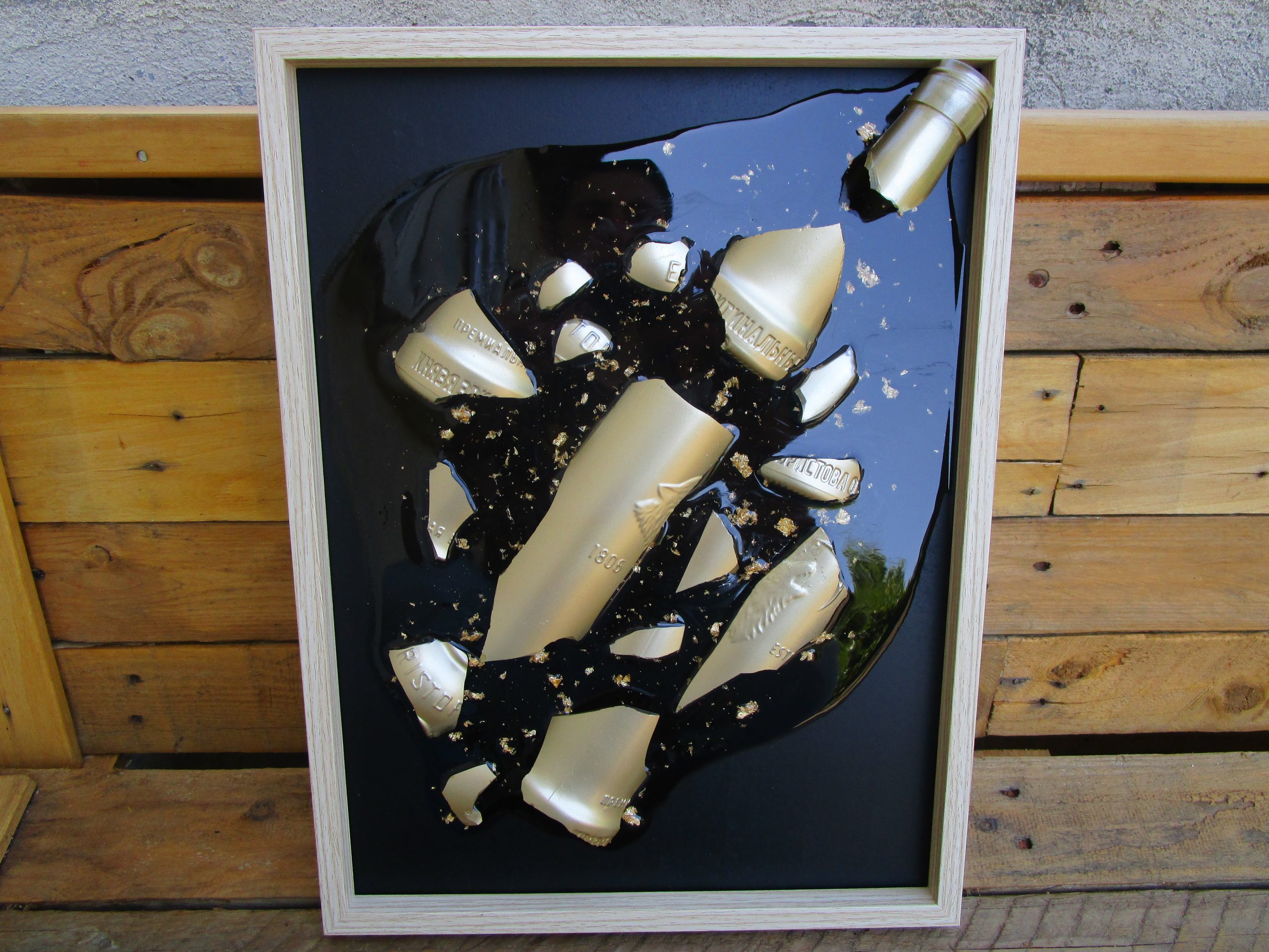 Fragment de Toi Cadre artistique fait main montrant des éclats dorés d'une bouteille dans de la résine transparente avec des incrustations de feuilles d'or, accroché sur un mur blanc.