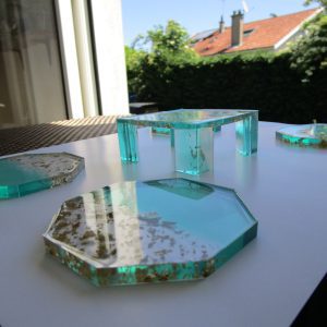 Boréal Doré "Service de dessous de verre 'Boréal Doré' fait main en résine vert turquoise et transparente avec incrustations de feuilles d'or, présenté avec son socle assorti."