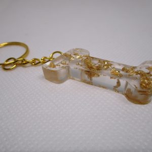 Porte-clés en résine transparente en forme de I, incrusté de feuilles d'or, avec un anneau doré et une chaîne.
