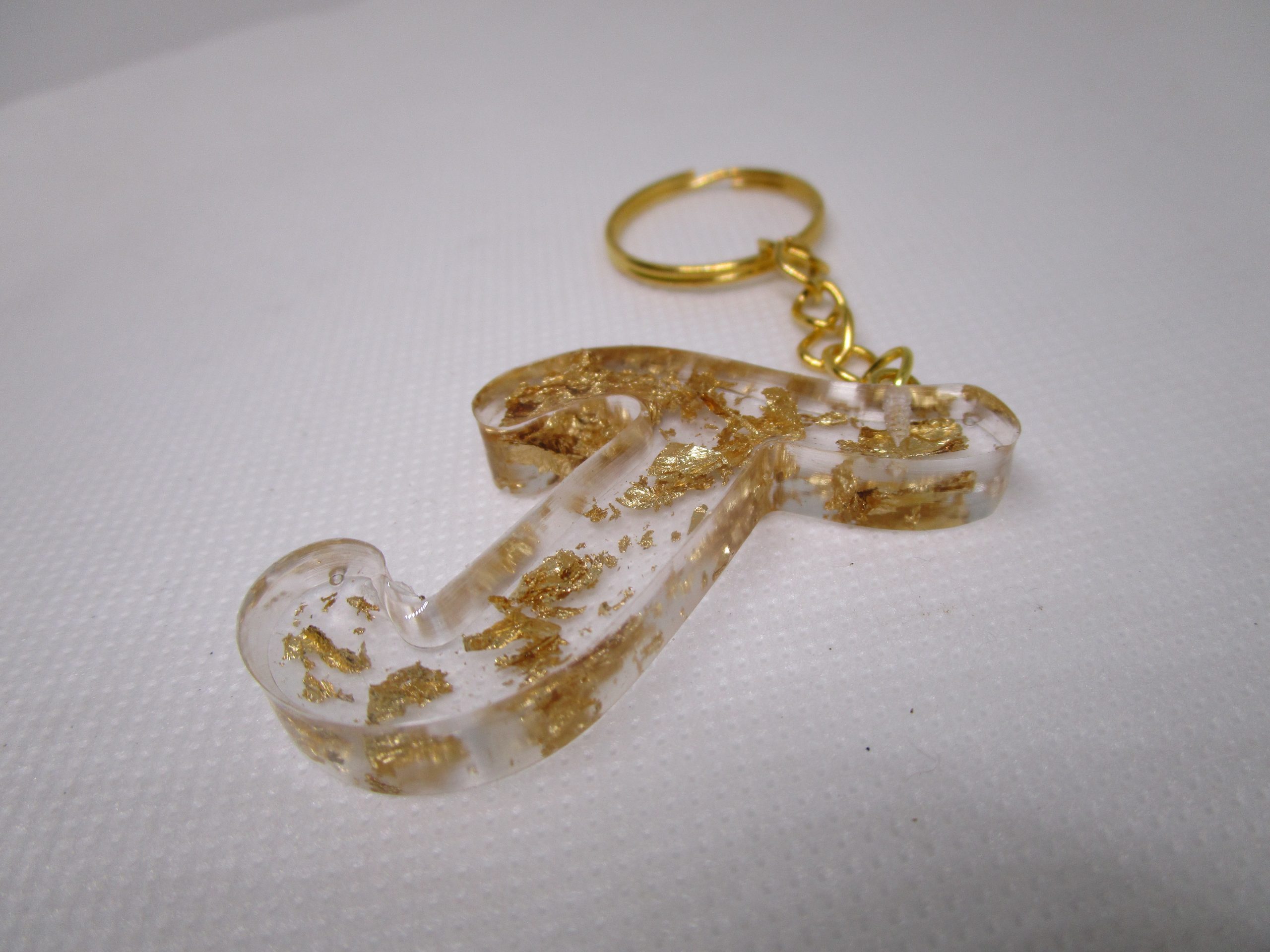 Porte-clés en résine transparente en forme de lettre "J", incrusté de feuilles d'or, avec un anneau doré et une chaîne.