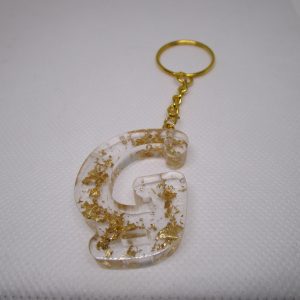 Porte-clés en résine transparente en forme de lettre "G", incrusté de feuilles d'or, avec un anneau doré et une chaîne.