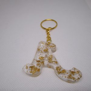 Porte-clés en résine transparente en forme de lettre "A", incrusté de feuilles d'or, avec un anneau doré et une chaîne.
