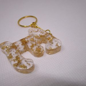 Porte-clés en résine transparente en forme de lettre "E", incrusté de feuilles d'or, avec un anneau doré et une chaîne.