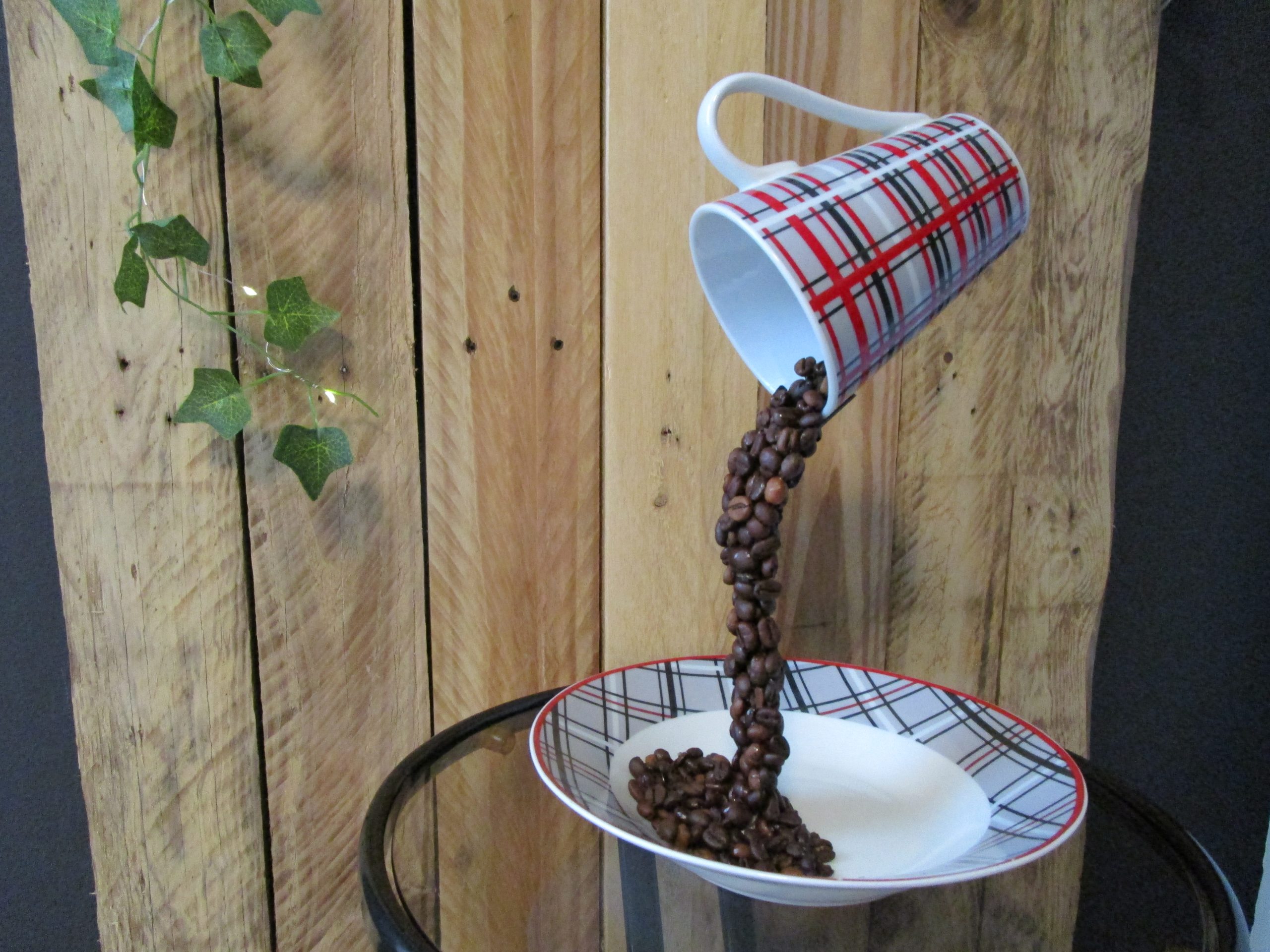 "Instant Figé". Sculpture artisanale Tasse écossaise rouge et grise. Grains de café bruns en suspension. Soucoupe blanche.